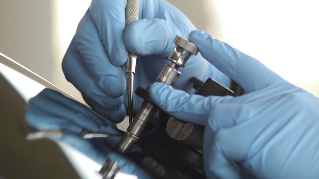Gloved hands using a resin injector to repair a windshield chip